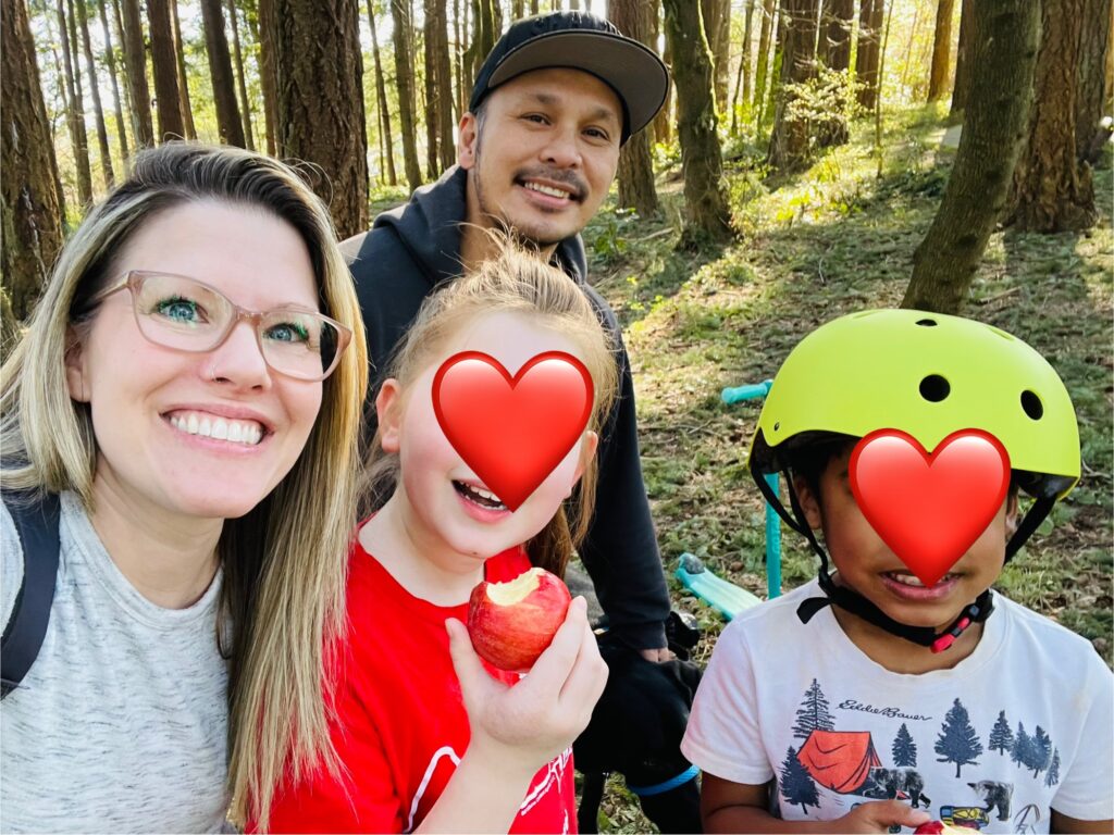 Cheryl, husband, and two children pictured with hearts over children's faces to protect their privacy