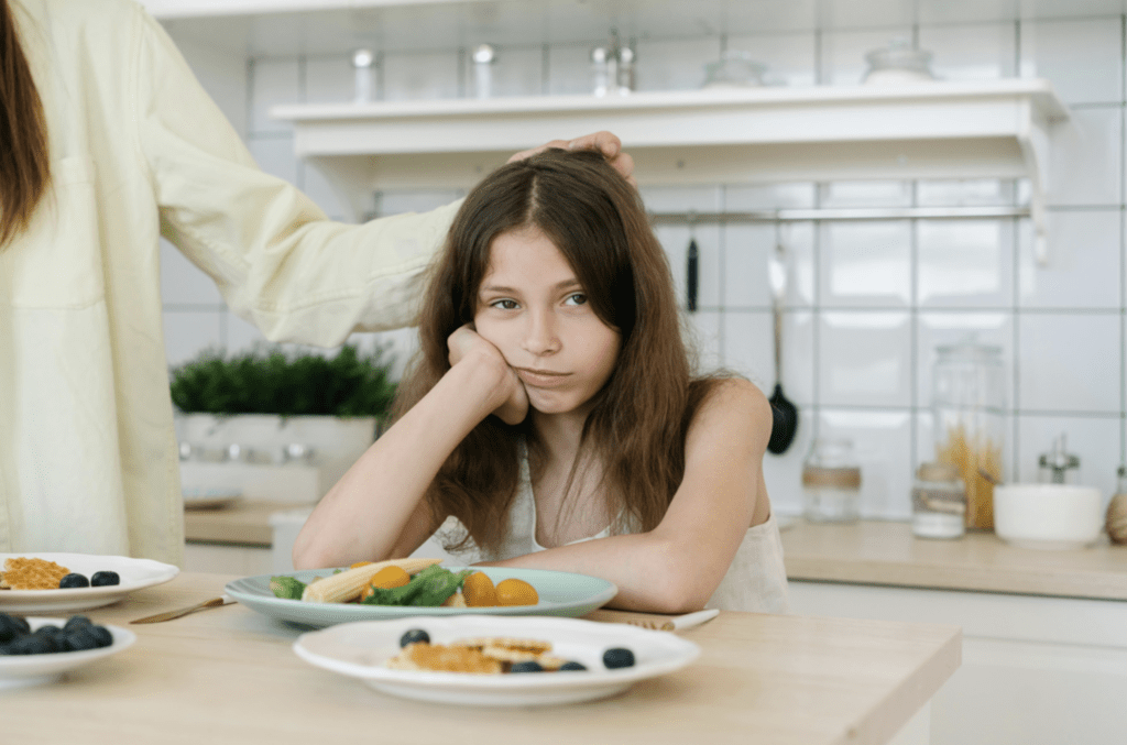 Girl with long brown hair visably upset by the meal in front of her